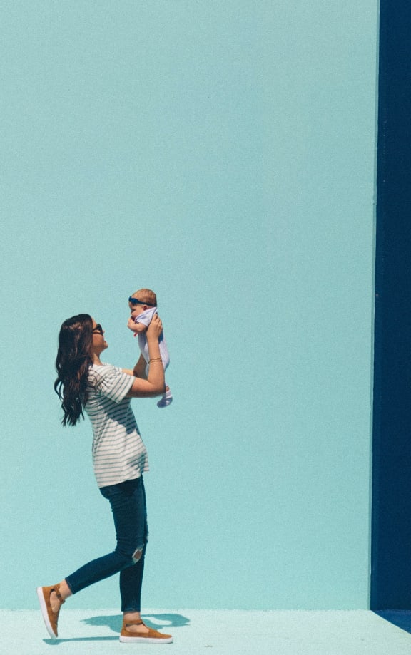a woman holding a baby in front of a blue and red wall