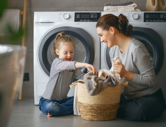 A woman and a child are doing laundry together.