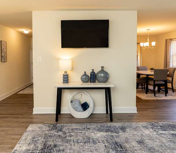 A living room with a television, a bench, and a rug at Painters Mill Apartments, Owings Mills, 21117