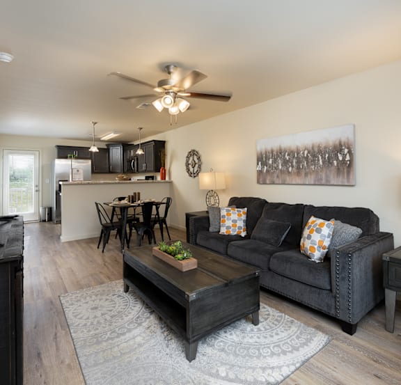 A living room with a black couch and a wooden coffee table.