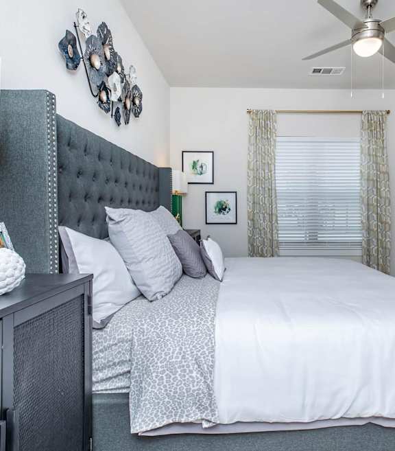 A bedroom with a large bed, a ceiling fan, and a black dresser. at Sienna at Westover Hills Apartments, San Antonio, TX 78253