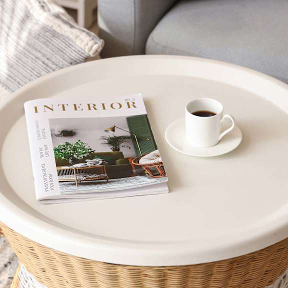 A magazine with the title Interior is on a table with a cup of coffee.
