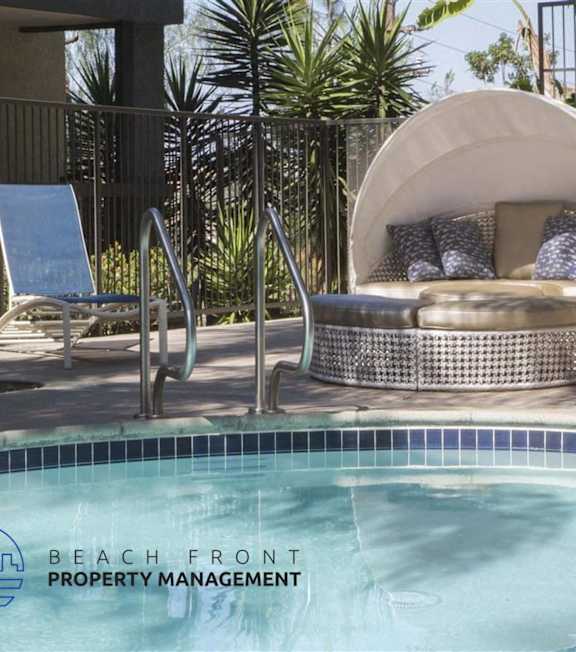 A pool with a hot tub and lounge chairs in front of a building.