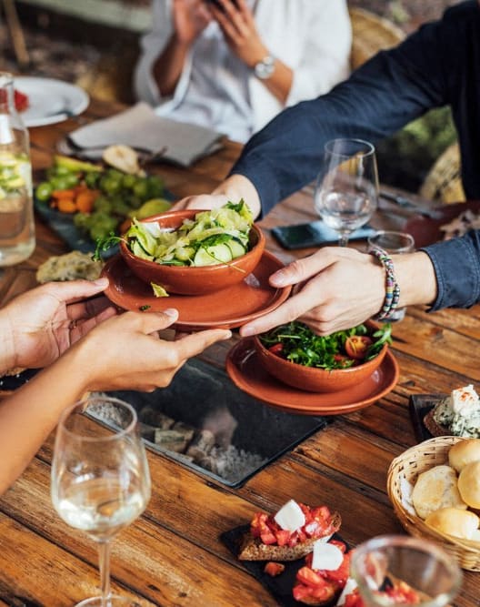 people sitting at a table with plates of food