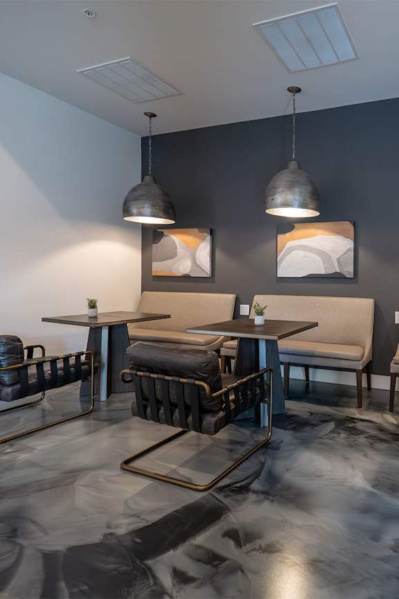 A room with black chairs and tables with a grey wall.