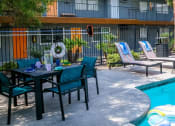 Thumbnail 10 of 23 - Community pool at fifteen 50 apartments in Las Vegas, NV, 89119 with lounge chairs and patio umbrellas