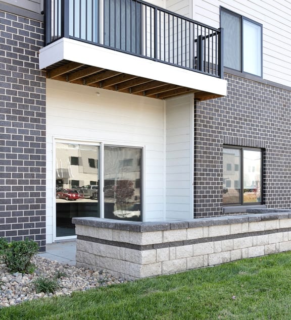 a front porch of a brick house with a stone wall and a balcony