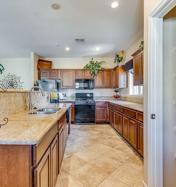 A kitchen with a marble counter top and wooden cabinets.