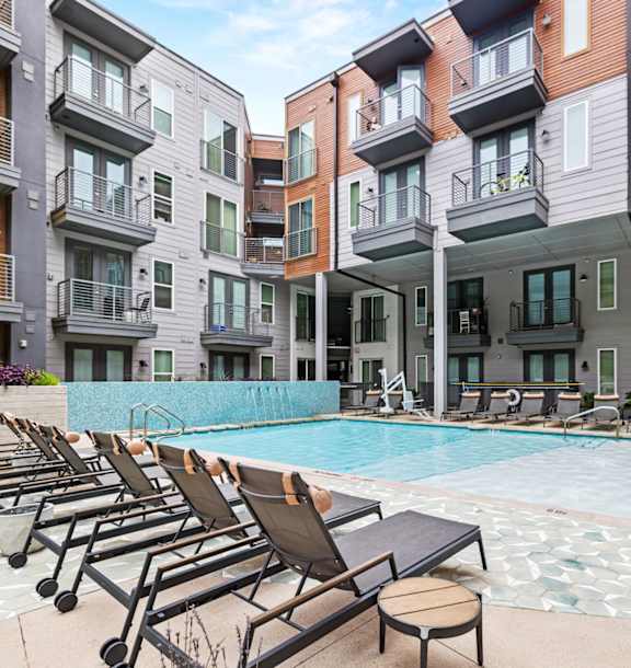 A swimming pool surrounded by lounge chairs and buildings.at Placemakr Downtown Austin, Austin