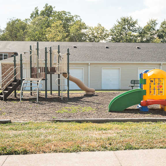 A playground with a yellow and green slide and a red and blue climbing frame.
