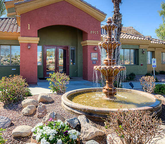 A house with a red roof and a fountain in front.