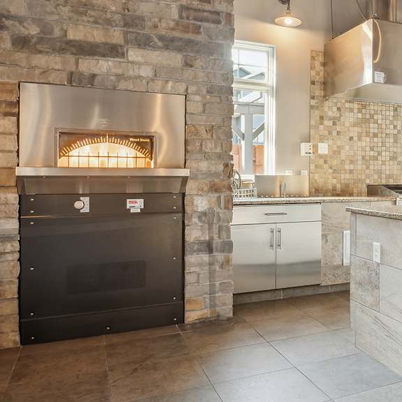 A modern kitchen with a stone fireplace and bar area.