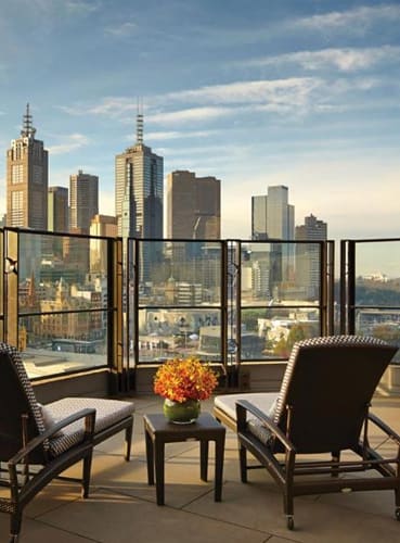 a balcony with two chairs and a table and a view of a city