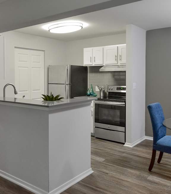 A kitchen with a bar area and a blue chair.
