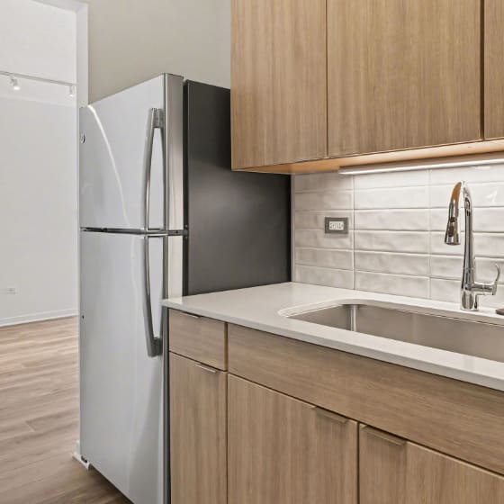 A kitchen with a white sink and a black fridge.