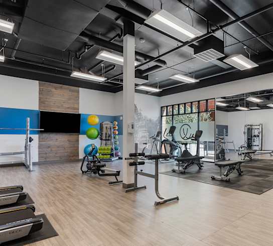 a gym with cardio equipment and weights on a wooden floor at City View St. George Apartments, Utah, 84770
