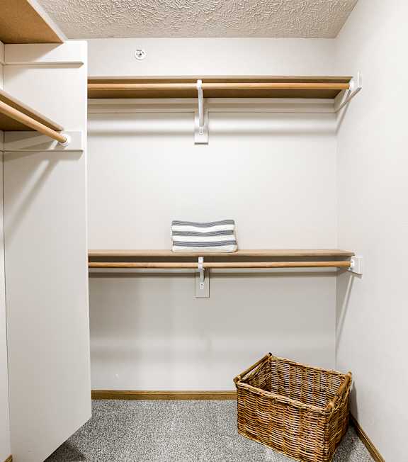 A small closet with a basket on the floor.