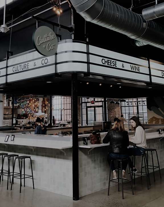 A restaurant with a counter and people sitting at it.