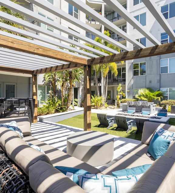 A modern outdoor seating area with a long couch and a table.