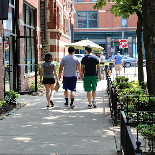 Two people walking down a sidewalk.