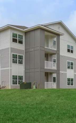 A large apartment complex with multiple buildings and green lawns in front.