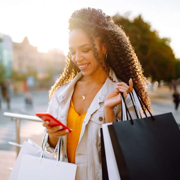 A woman with shopping bags is looking at her phone.