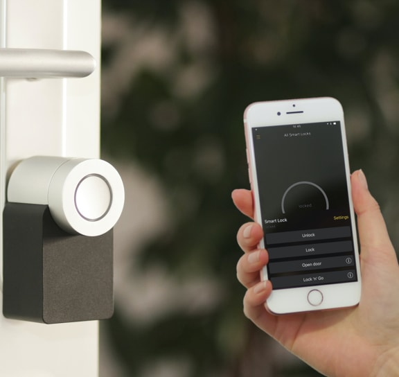 a person holding a cell phone in their hand next to a doorbell