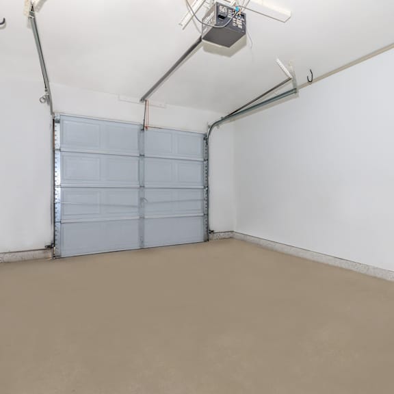 A room with a closed grey garage door and a white wall.