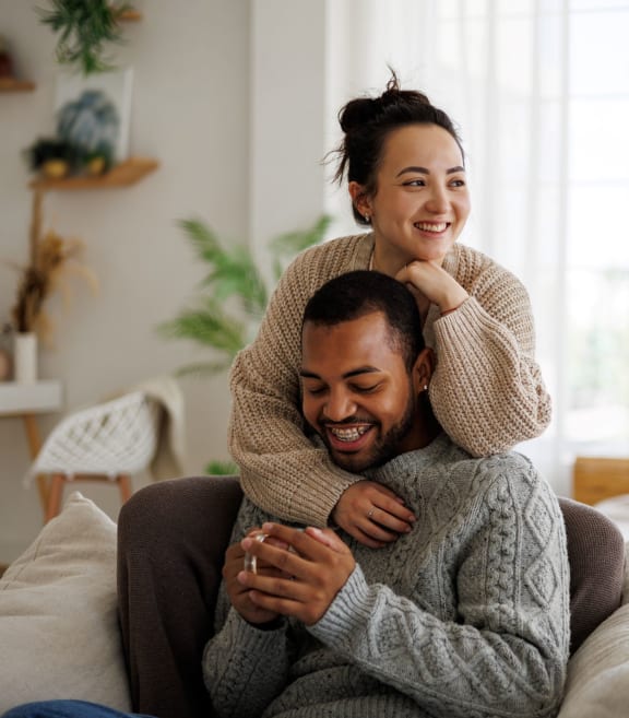 a man sitting on a couch with a woman on his shoulders at Maxfield Lofts Apartments, Los Angeles