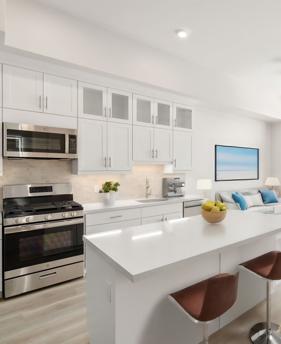 an open kitchen and living room with white cabinets and stainless steel appliances