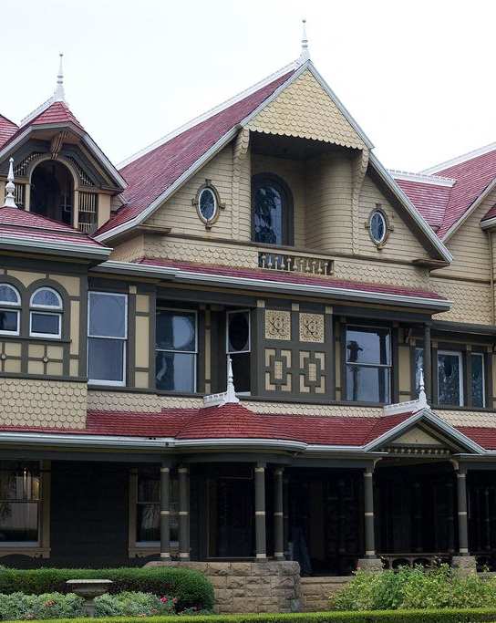A Victorian style house with a red roof and a balcony.