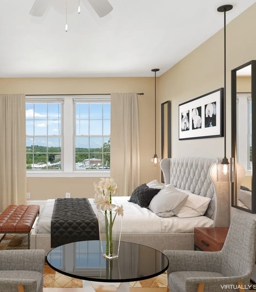 a bedroom with a bed and two chairs in front of a window