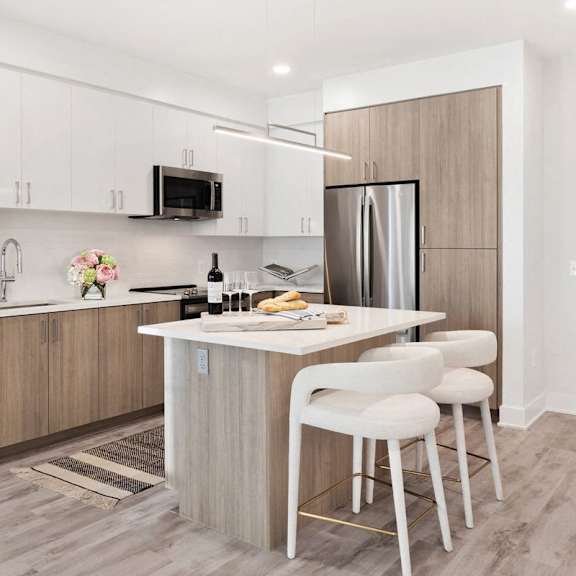 A kitchen with a refrigerator, microwave, and sink.