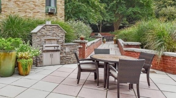 a patio with a table and chairs and a brick wall at The Saratoga Apartments, Washington, DC 20008