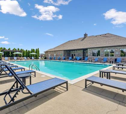 A pool with sun loungers and a building in the background.