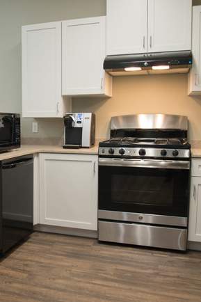 A kitchen with white cabinets and a black fridge.