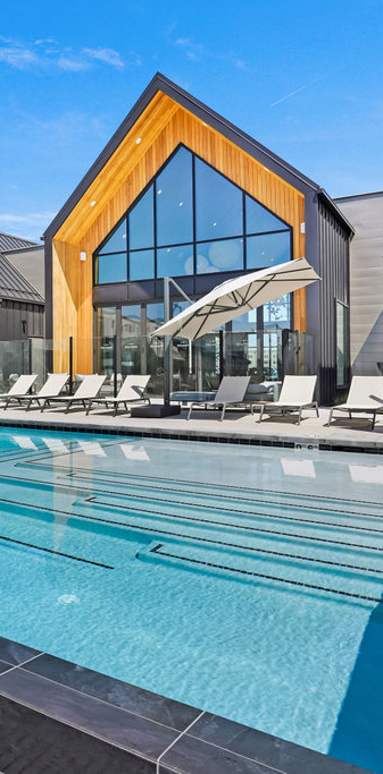 A modern building with a pool in the foreground and snow-capped mountains in the background.