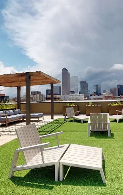 A rooftop patio with white furniture and a city skyline in the background.