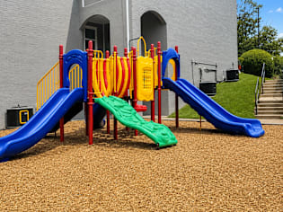 A playground with a blue slide and a green slide.