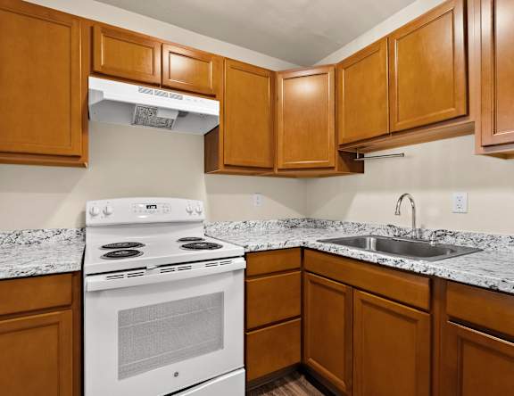 A kitchen with a white stove and wooden cabinets.