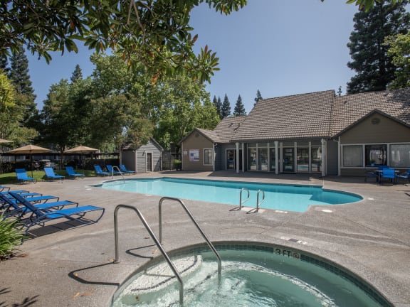 a swimming pool with chairs and a house in the background at Bishop's Court Apartments, Rancho Cordova, CA