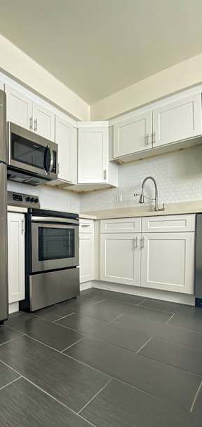 A modern kitchen with a stainless steel refrigerator and microwave.
