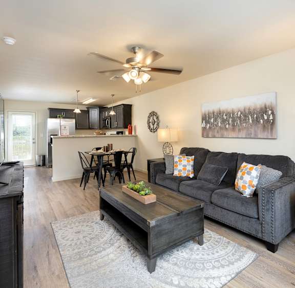 A living room with a black couch and a wooden coffee table.