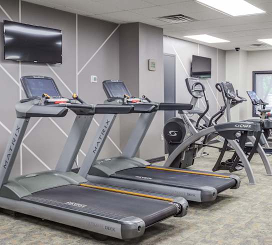 a gym with treadmills and other exercise equipment and a television