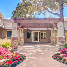 A building with a covered walkway entrance surrounded by flowers.
