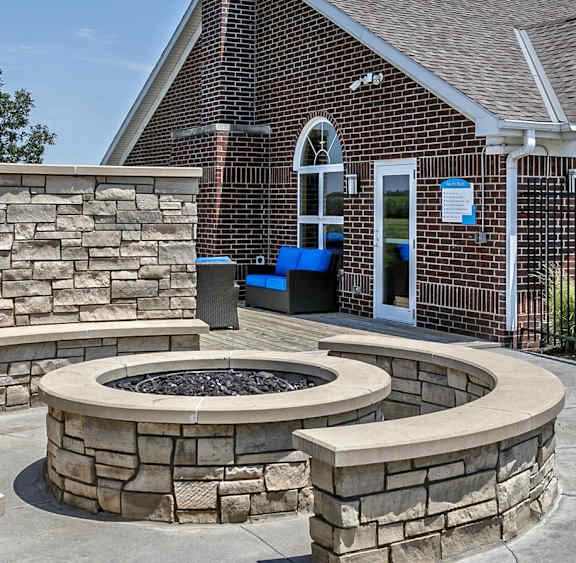 A patio with blue cushions and grey furniture in front of a brick building.