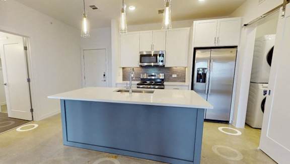 A modern kitchen with a blue island and stainless steel appliances.