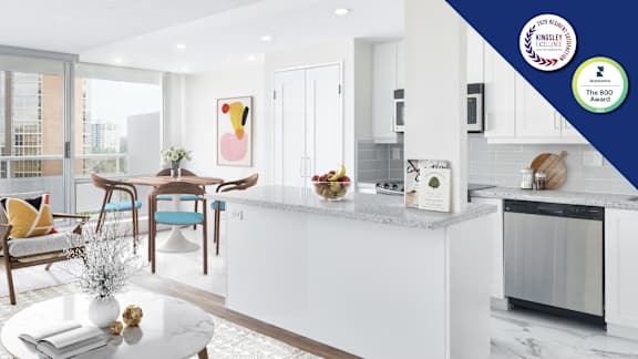A modern living room with a kitchen area in the background.