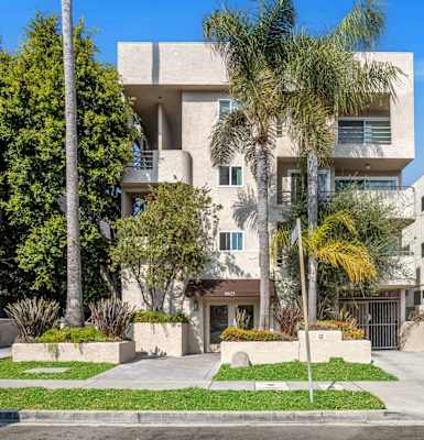 A modern residential building with a well-maintained lawn and trees.