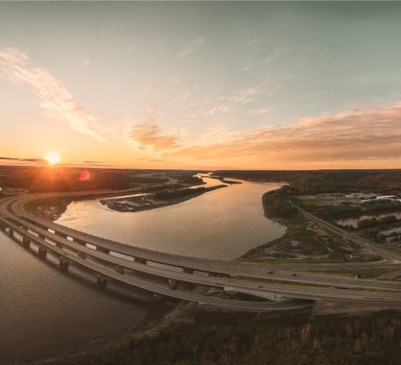 a sunset over a bridge over a river